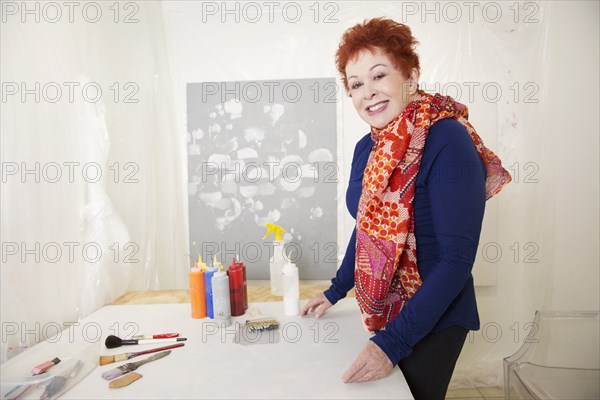 Older Caucasian artist standing at crafts table