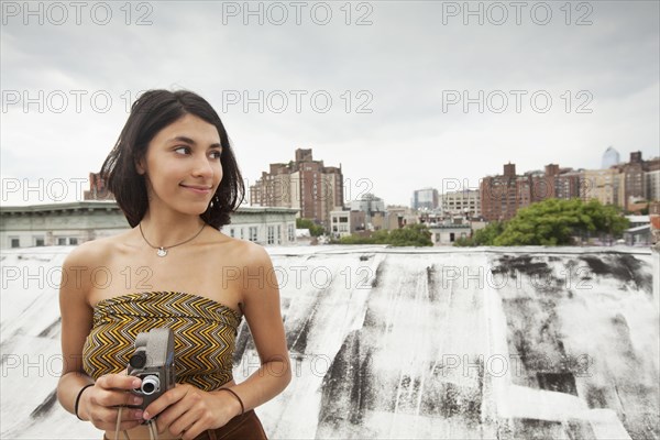 Mixed Race woman on rooftop holding video camera