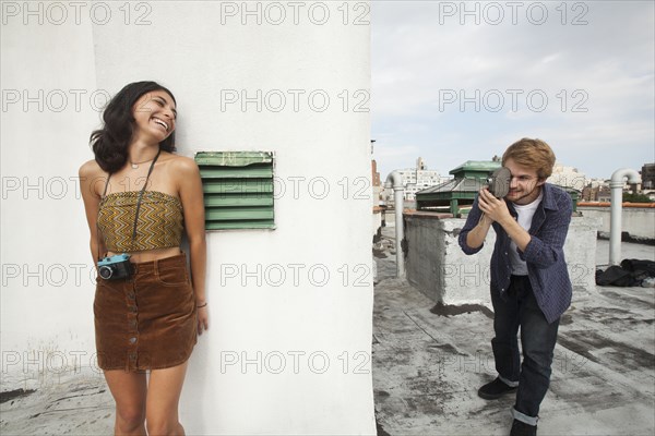 Mixed Race couple playing on rooftop with video camera