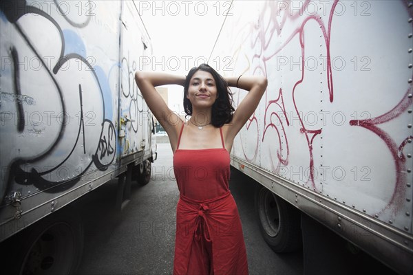Mixed Race woman between semi-trucks with graffiti