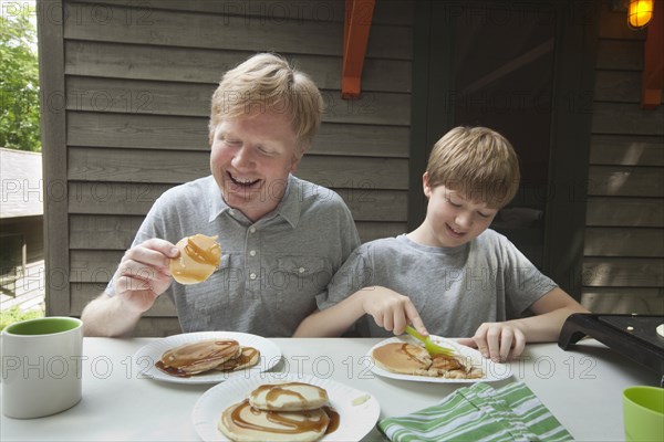 Caucasian father and son eating pancakes outdoors