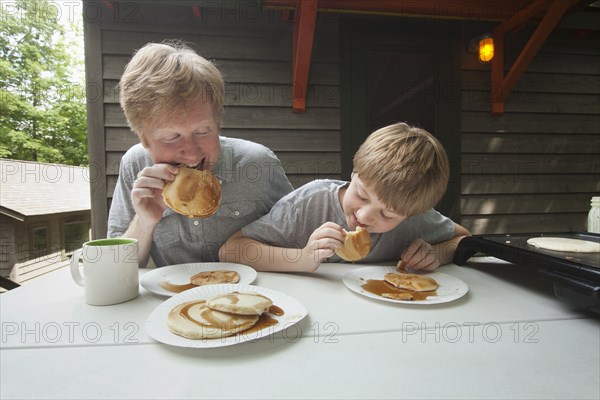 Caucasian father and son eating pancakes outdoors