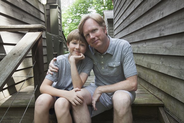 Caucasian father and son hugging on wooden staircase