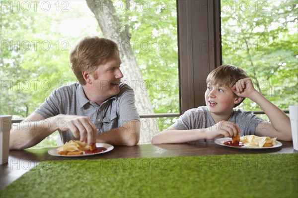 Caucasian father and son dipping food in ketchup