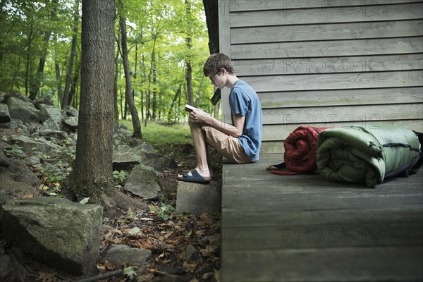 Caucasian boy reading book on wooden patio