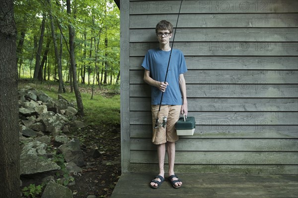 Caucasian boy holding fishing rod at cabin