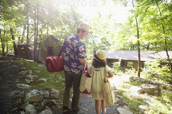 Caucasian father and daughter carrying bags at cabin