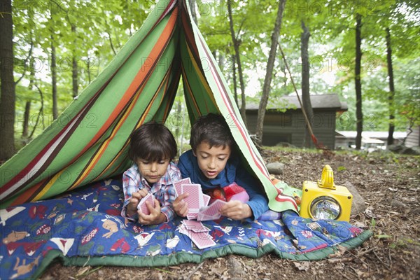 Mixed Race boys playing card game in blanket fort