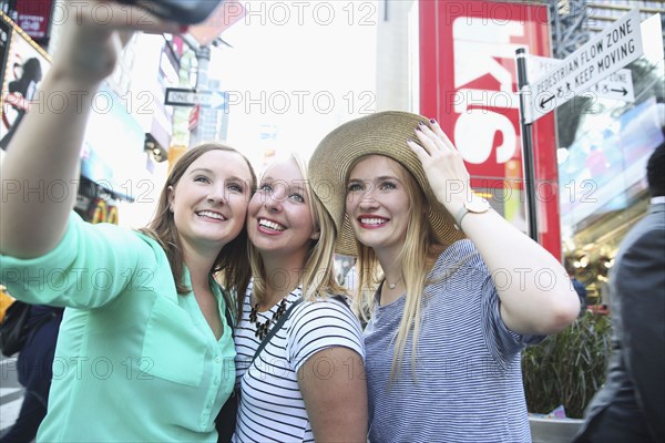 Smiling Caucasian woman posing for cell phone selfie in city