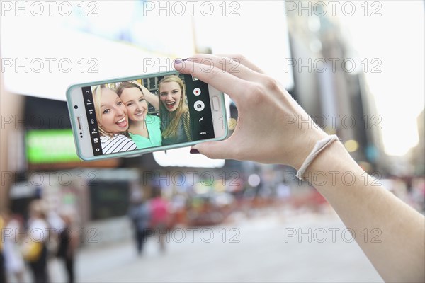 Arm of Caucasian woman posing for cell phone selfie with friends