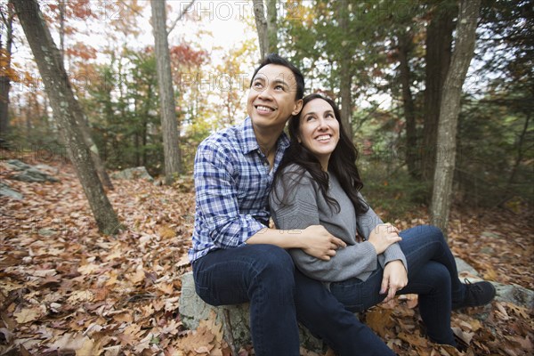 Couple sitting on rock in forest during autumn