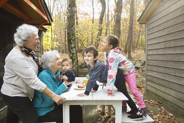 Grandmothers playing with grandchildren at breakfast table outdoors