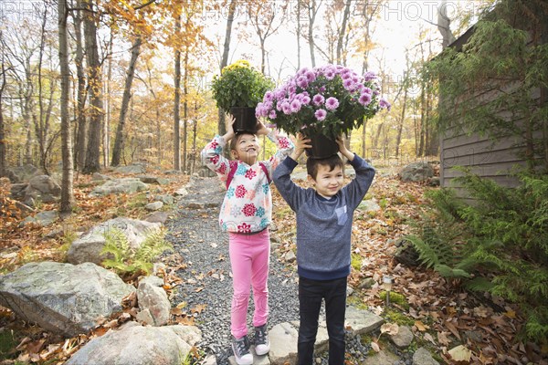 Mixed Race brother and sister balancing flowers on heads