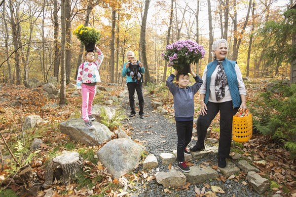 Brother and sister balancing flowers on heads near grandmothers