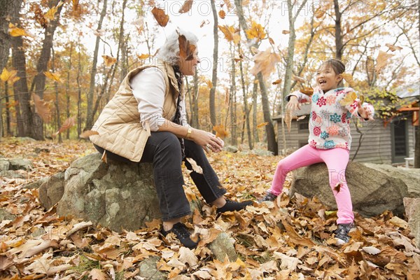 Grandmother and granddaughter playing with autumn leaves