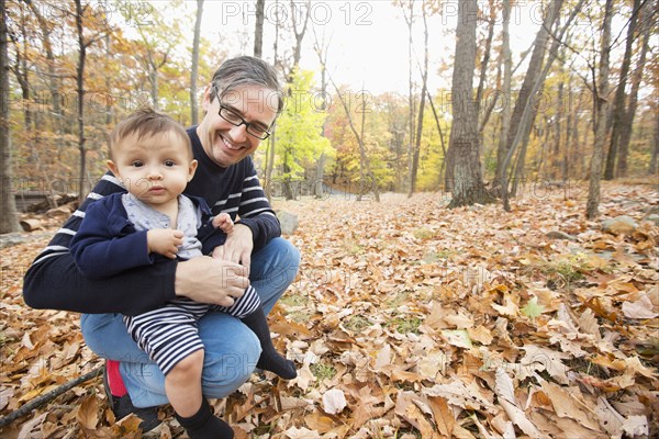 Father holding baby son outdoors in autumn