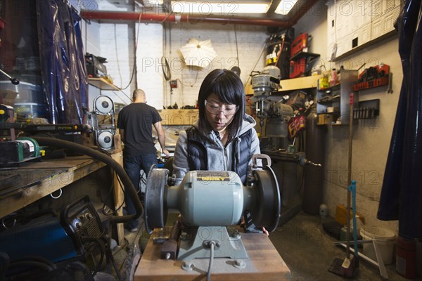 Man and woman using machinery in workshop