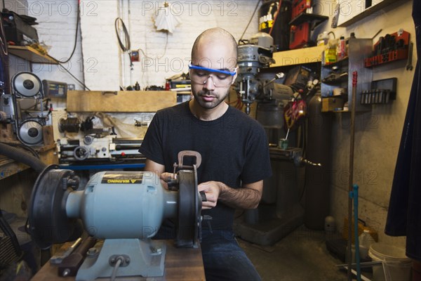 Mixed Race man using machinery in workshop