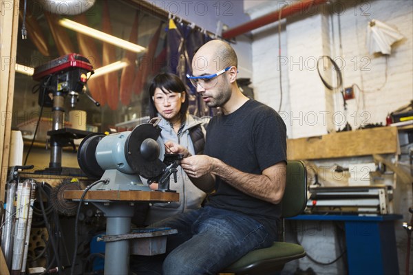 Man and woman using machinery in workshop