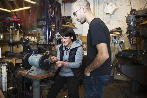 Mixed Race man using machinery in workshop