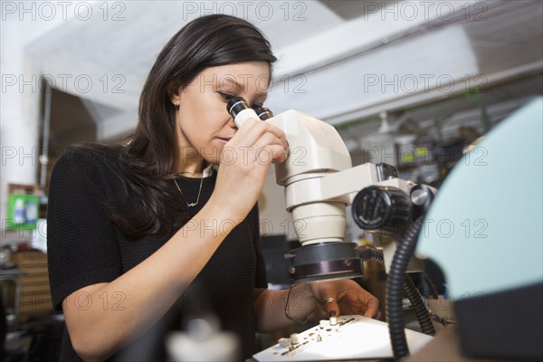 Mixed Race woman using microscope