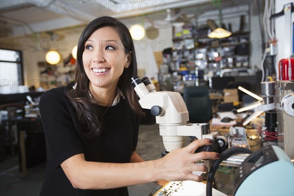 Mixed Race woman using microscope