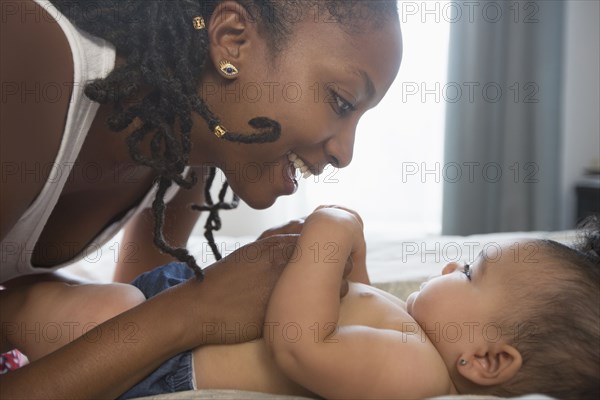 Mother fussing over baby daughter on bed