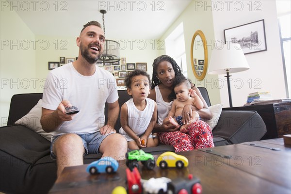 Parent watching television with son and daughter