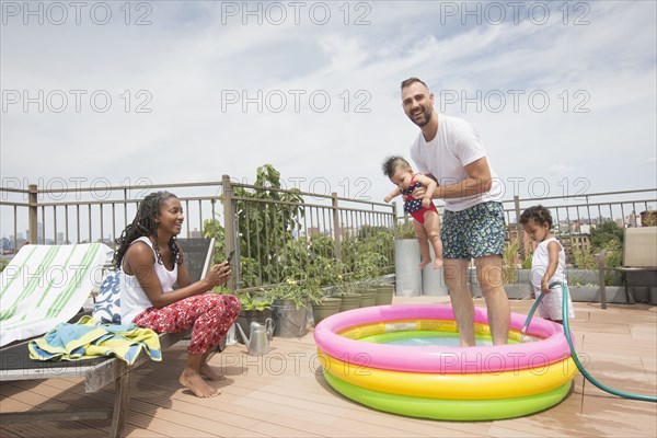 Parents playing with children in inflatable swimming pool