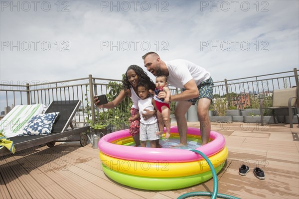 Parents posing for selfie with children in inflatable swimming pool