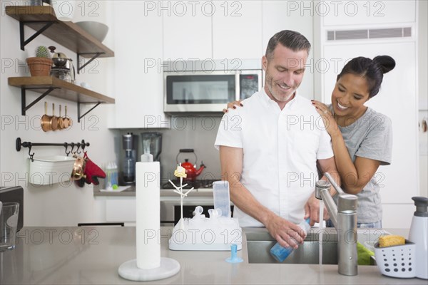 Woman watching man washing baby bottle
