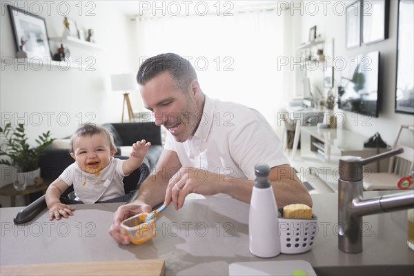 Father feeding happy baby son