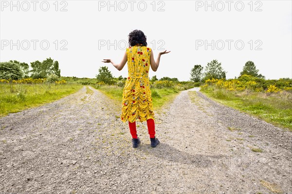 Asian woman shrugging at split in road