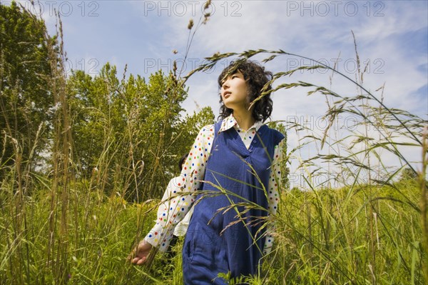 Asian woman walking through tall grass