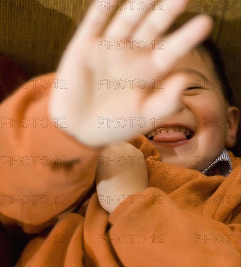 Asian boy holding hand in front of face