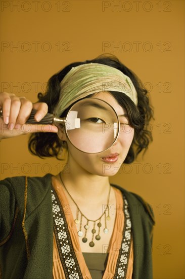 Asian woman looking through magnifying glass