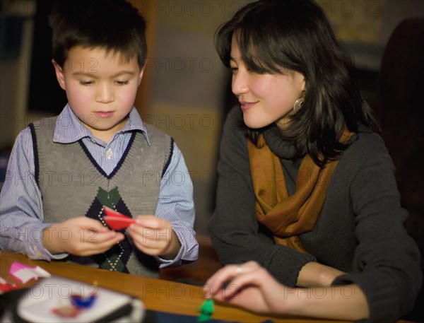 Asian mother and son making origami