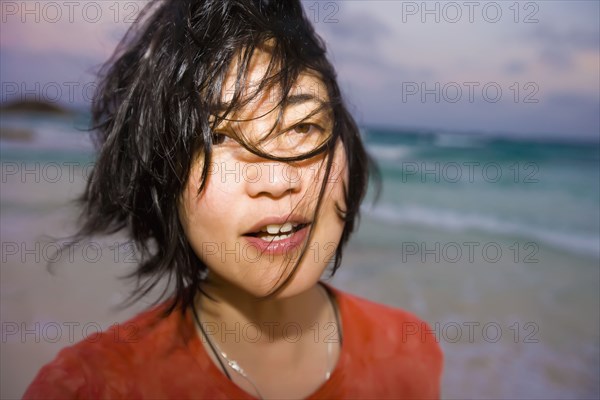 Asian woman with hair blowing at beach