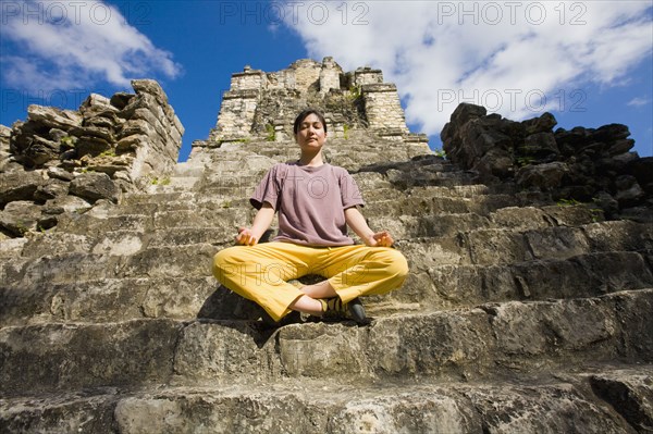 Asian woman meditating on temple ruins