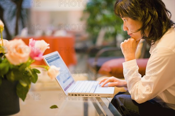 Asian woman using laptop in livingroom