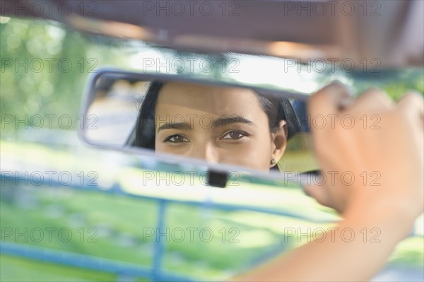 Hispanic woman adjusting rear view mirror in car