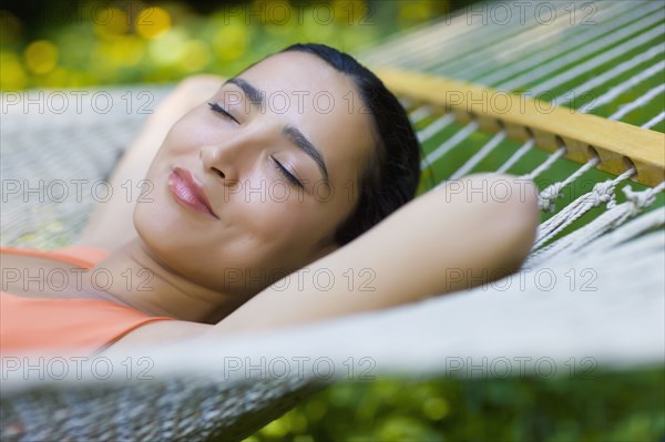 Hispanic woman laying in hammock