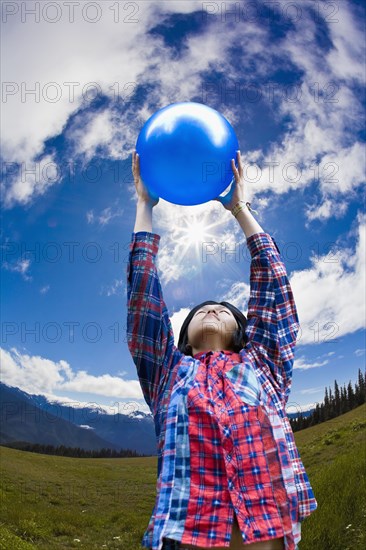 Asian man lifting ball in remote field