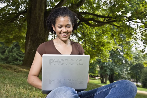 Mixed race woman typing on laptop outdoors