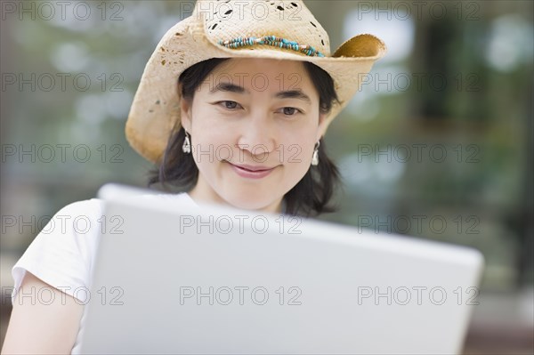 Japanese woman typing on laptop wearing cowboy hat