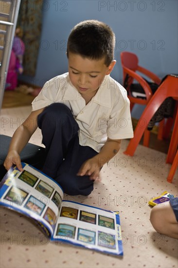 Asian boy reading magazine in bedroom