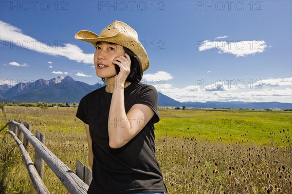 Japanese woman talking on cell phone in country field