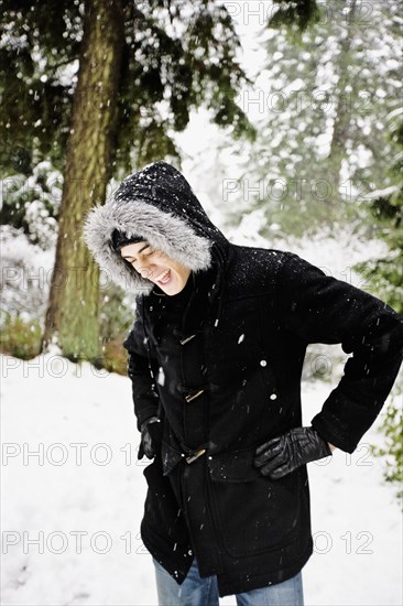 Mixed race man in hooded coat outdoors in snowfall