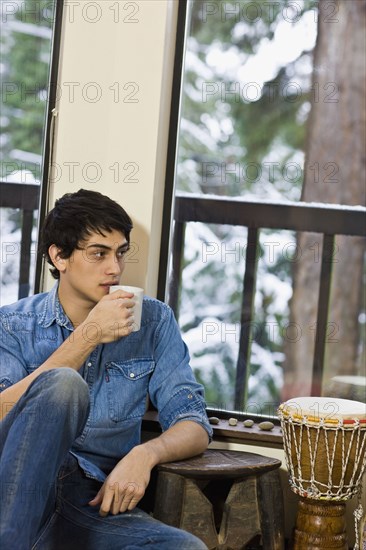 Mixed race man drinking coffee in living room