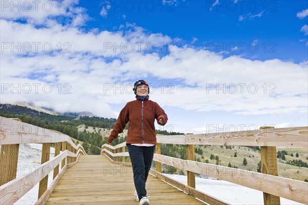 Japanese woman walking across wooden bridge